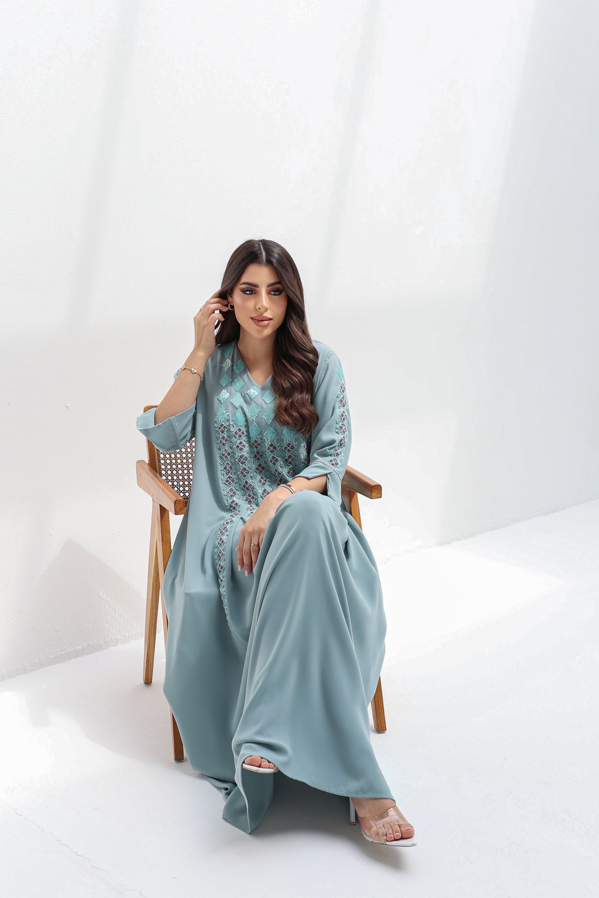  Seated full-length view of dusty blue embroidered kaftan with a relaxed flowing silhouette

