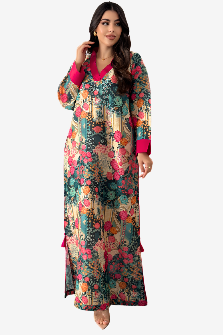A woman modeling a long-sleeved maxi dress with a dense floral and botanical print in teal, pink, orange, and beige tones, featuring a solid bright pink V-neckline and cuffs.