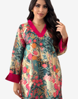 A woman modeling a long-sleeved floral print tunic with a vibrant pink V-neck and cuffs, set against a plain light gray background.