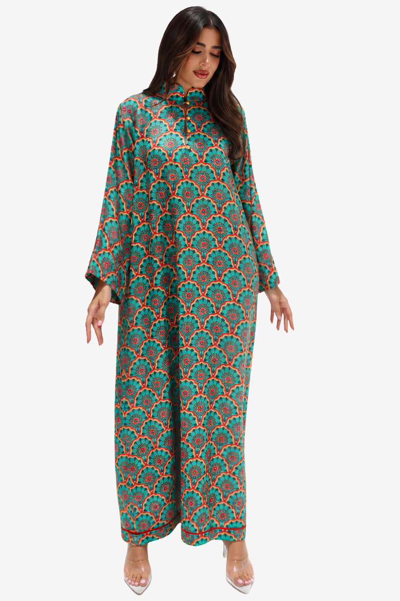 A woman modeling a long-sleeve, high-neck maxi dress with a colorful geometric and floral pattern in teal, orange, and green, set against a plain light gray background.