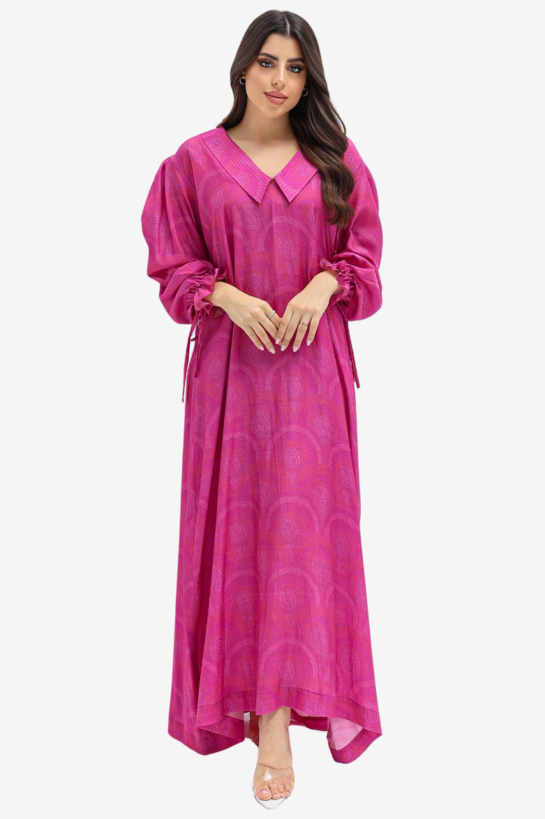 A woman modeling a long magenta pink kaftan dress with a V-neck, long sleeves, and a subtle circular jacquard pattern, set against a plain light gray background.