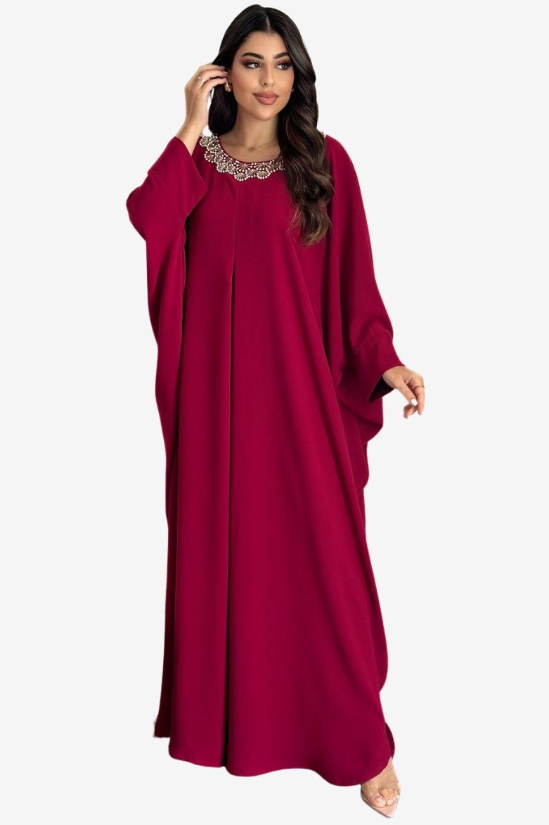 A woman modeling a long, flowing magenta maxi dress with wide draped sleeves and a decorative silver-toned collar, set against a plain light gray background.