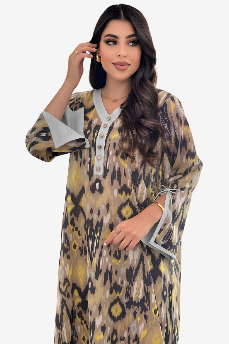 A woman modeling a long kaftan dress with a beige, brown, and black leopard print pattern and light gray trim details.