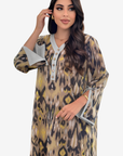 A woman modeling a long kaftan dress with a beige, brown, and black leopard print pattern and light gray trim details.
