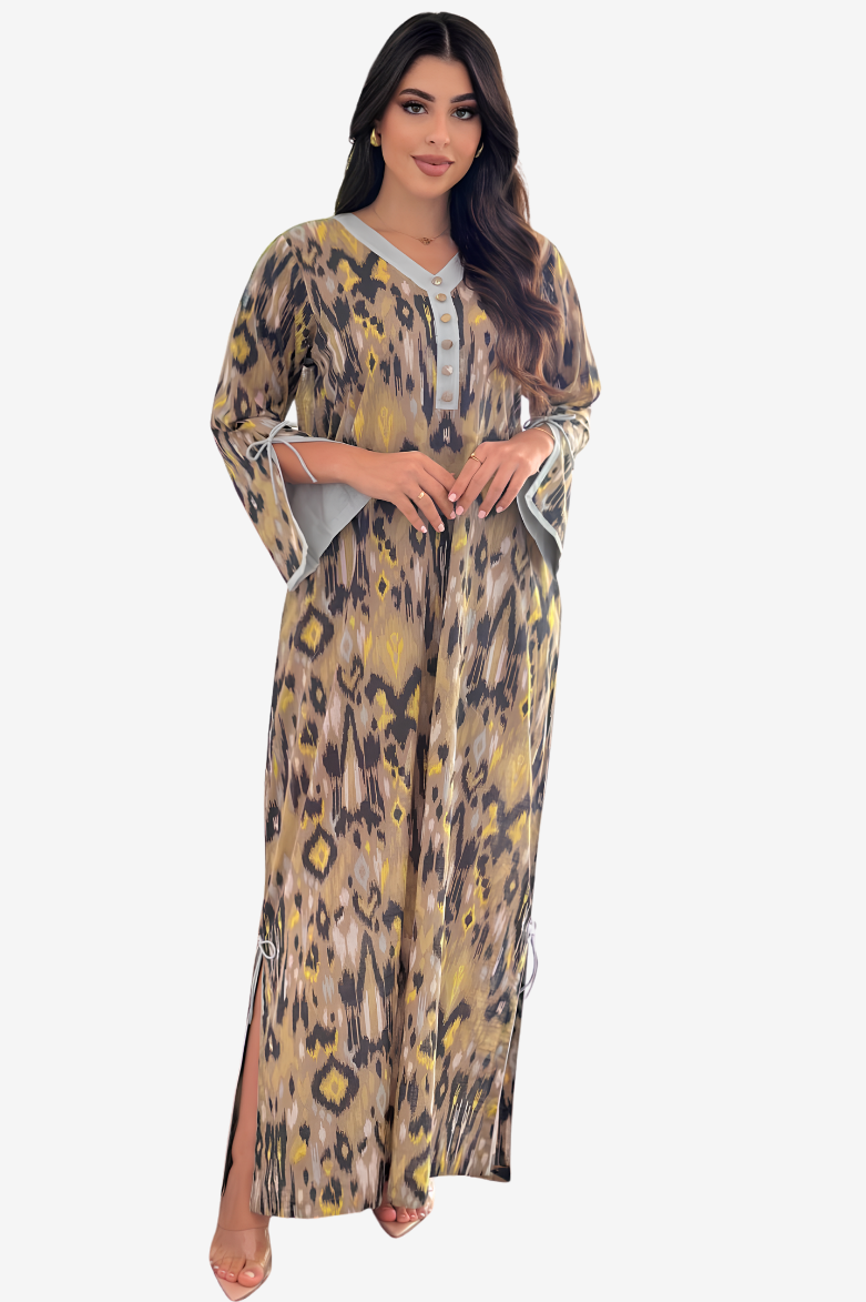 A woman modeling a long kaftan dress with a beige, brown, and yellow leopard print pattern and gray trim, set against a plain light gray background.