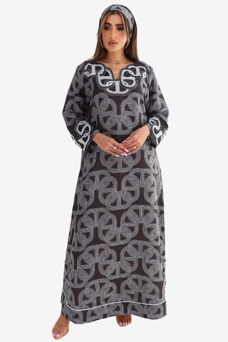 A woman modeling a long-sleeved gray abaya dress with a white geometric pattern and a matching headscarf, set against a plain light gray background.