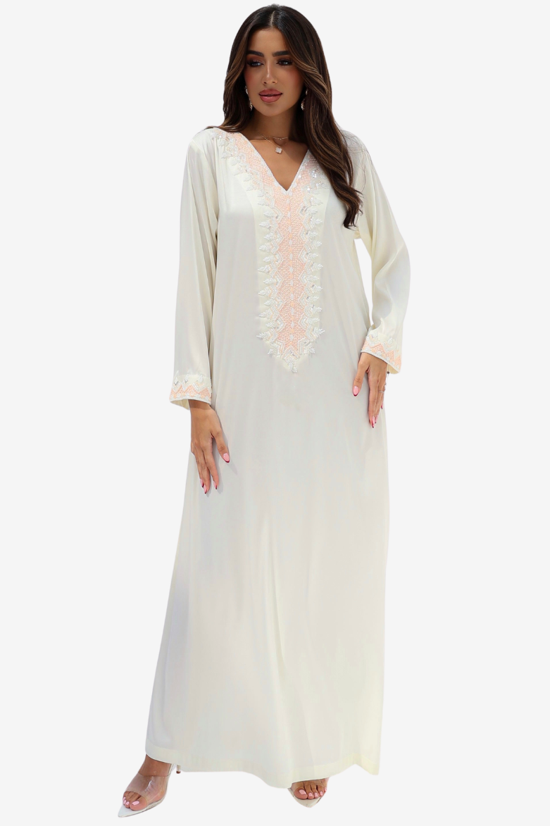 A woman modeling a long white or off-white maxi dress with a V-neckline and delicate pale pink lace detailing down the front, set against a plain light gray background.