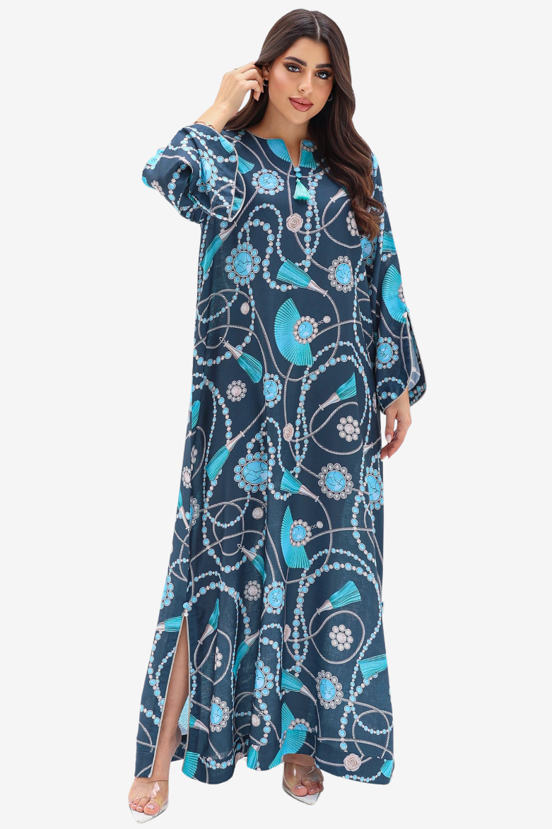 A woman modeling a long navy blue kaftan dress with a vibrant turquoise, white, and light pink floral and vine pattern, set against a plain light gray background.