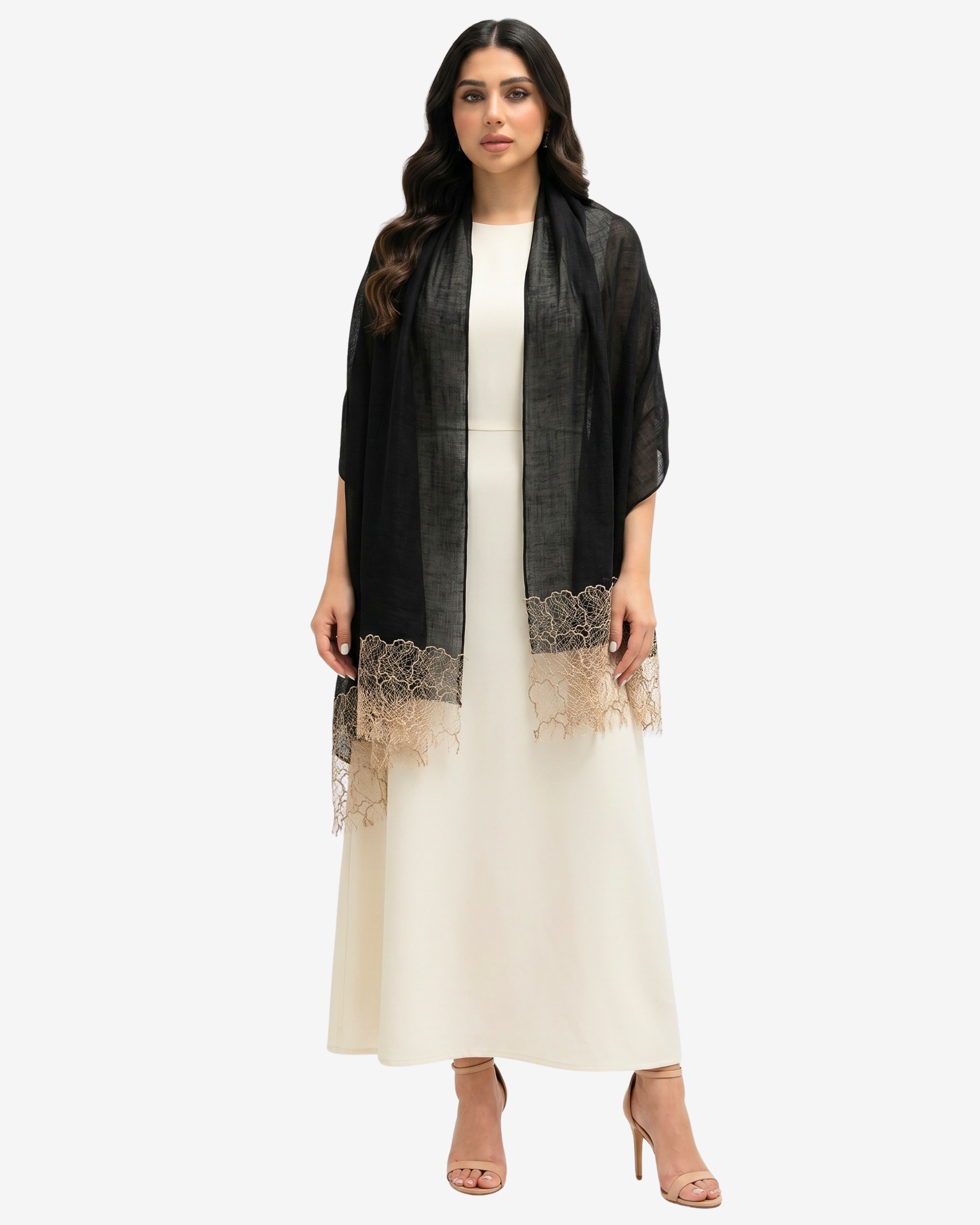 A woman modeling a black sheer open-front cardigan with beige lace trim over a cream maxi dress and nude high heels, against a light gray studio background.