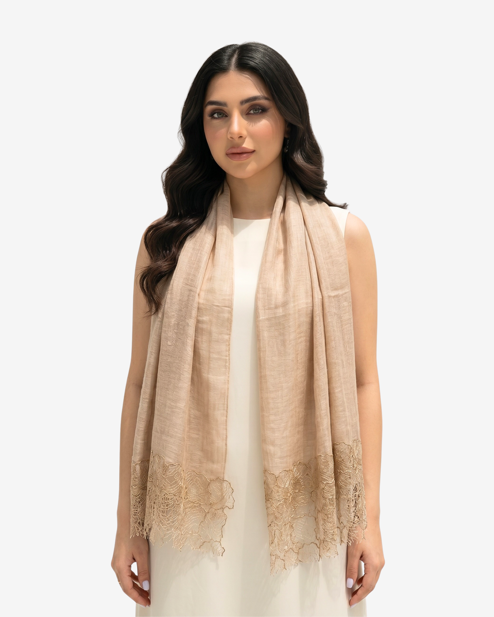 A woman modeling a light beige linen shawl with delicate floral lace trim at the ends, worn over a white sleeveless dress against a plain light gray background.