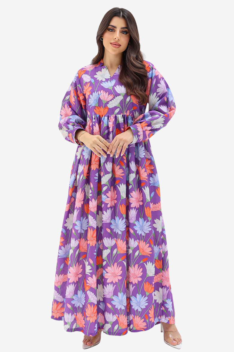 A woman modeling a long-sleeved maxi dress with a purple base and a colorful floral print in pink, orange, and light blue, set against a plain light gray background.
