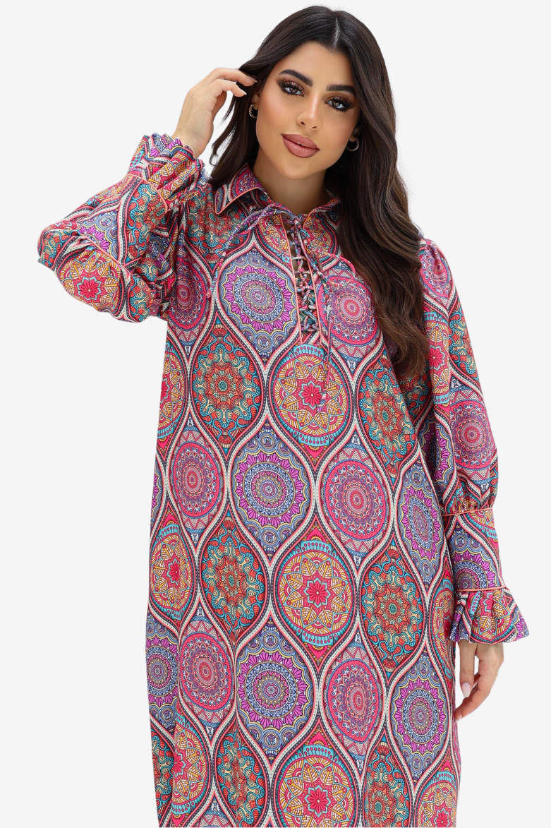 A woman modeling a long-sleeve collared dress with a colorful mandala pattern in pink, purple, blue, and orange on a light gray background.