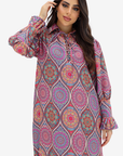 A woman modeling a long-sleeve collared dress with a colorful mandala pattern in pink, purple, blue, and orange on a light gray background.