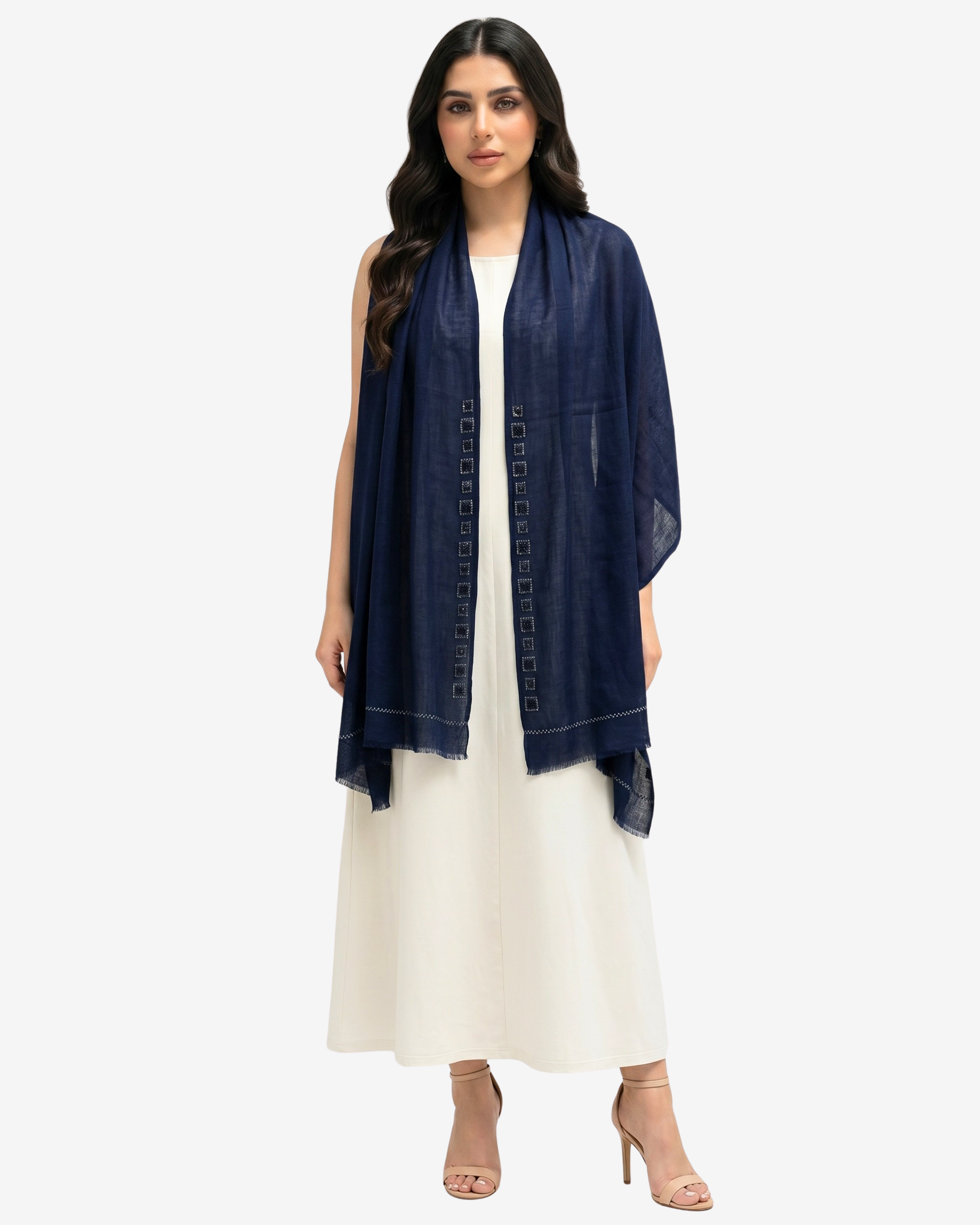 A woman modeling a navy blue shawl with geometric embroidered detailing down the center, worn over a white maxi dress against a light gray background.