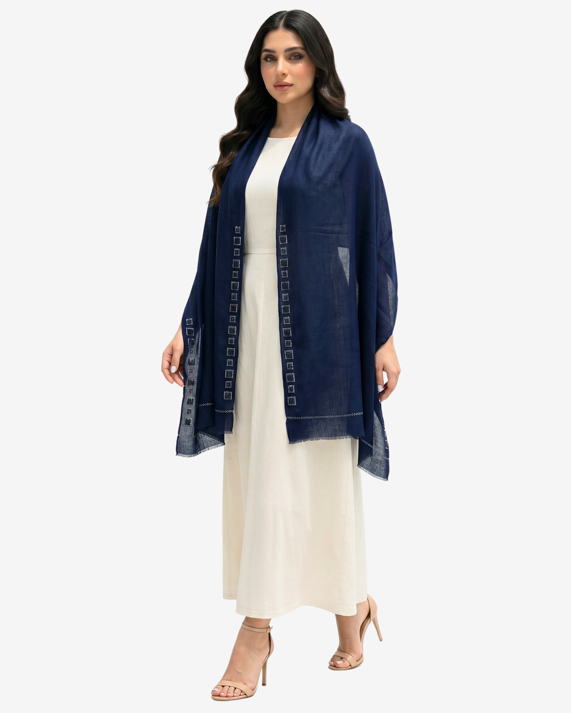 A woman modeling a navy blue open-front shawl draped over a cream-colored dress, standing against a light gray studio background.