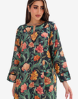 A woman wearing a long-sleeve floral print tunic dress with a keyhole neckline and black trim, set against a plain light gray background.