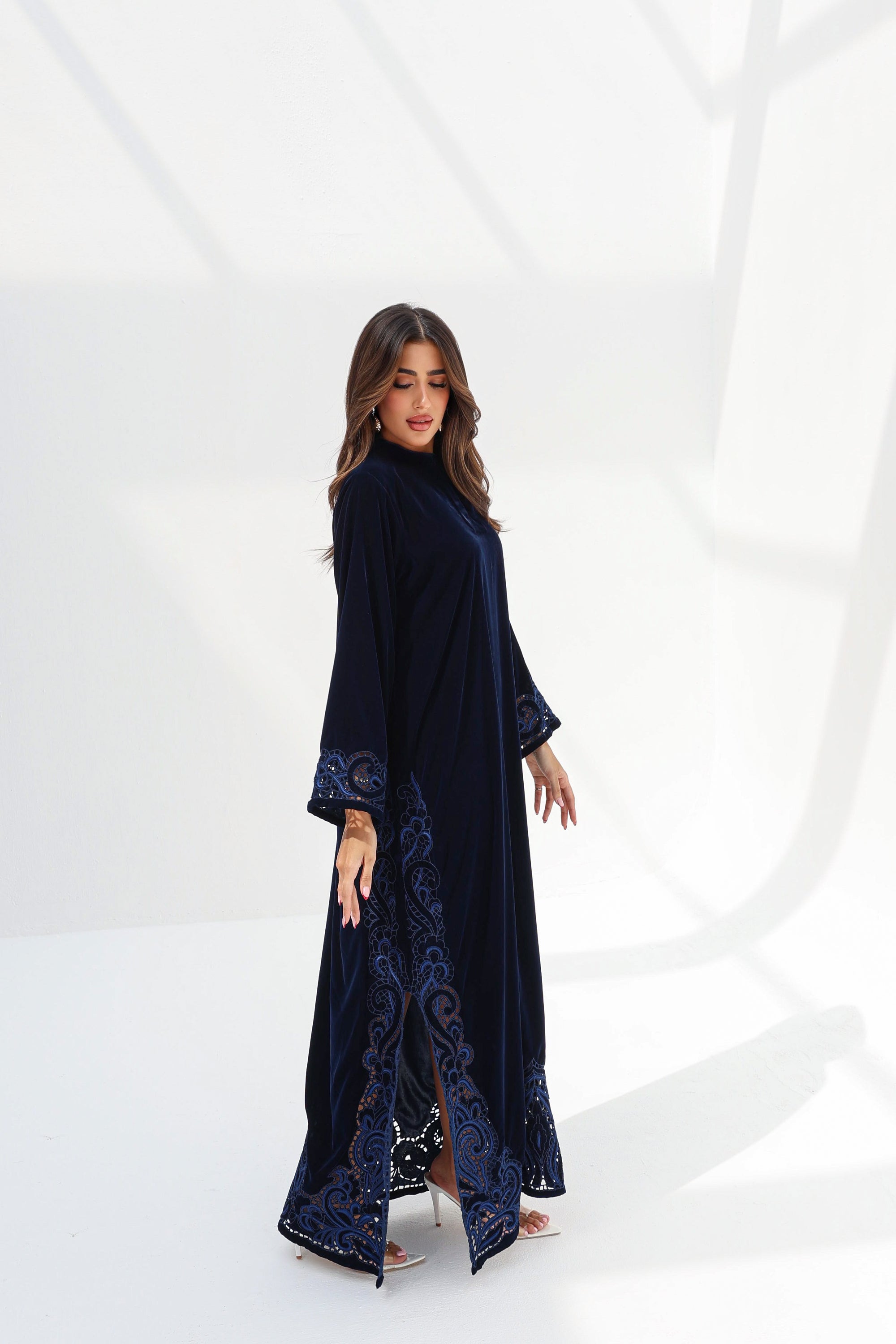 Full-length side view of navy velvet jalabiya showing the embroidered hem and side slit
