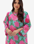 A woman modeling a light blue kaftan dress with a vibrant pink and green floral print, set against a plain light gray background.
