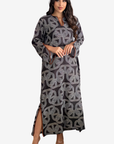 A woman modeling a long-sleeved maxi dress with a dark gray and light gray geometric interlocking pattern, set against a plain light gray background.