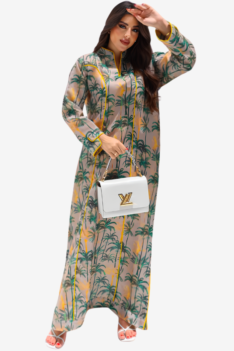 A woman modeling a long-sleeved maxi dress with a green palm tree print on a beige background, holding a white handbag with a gold LV logo.