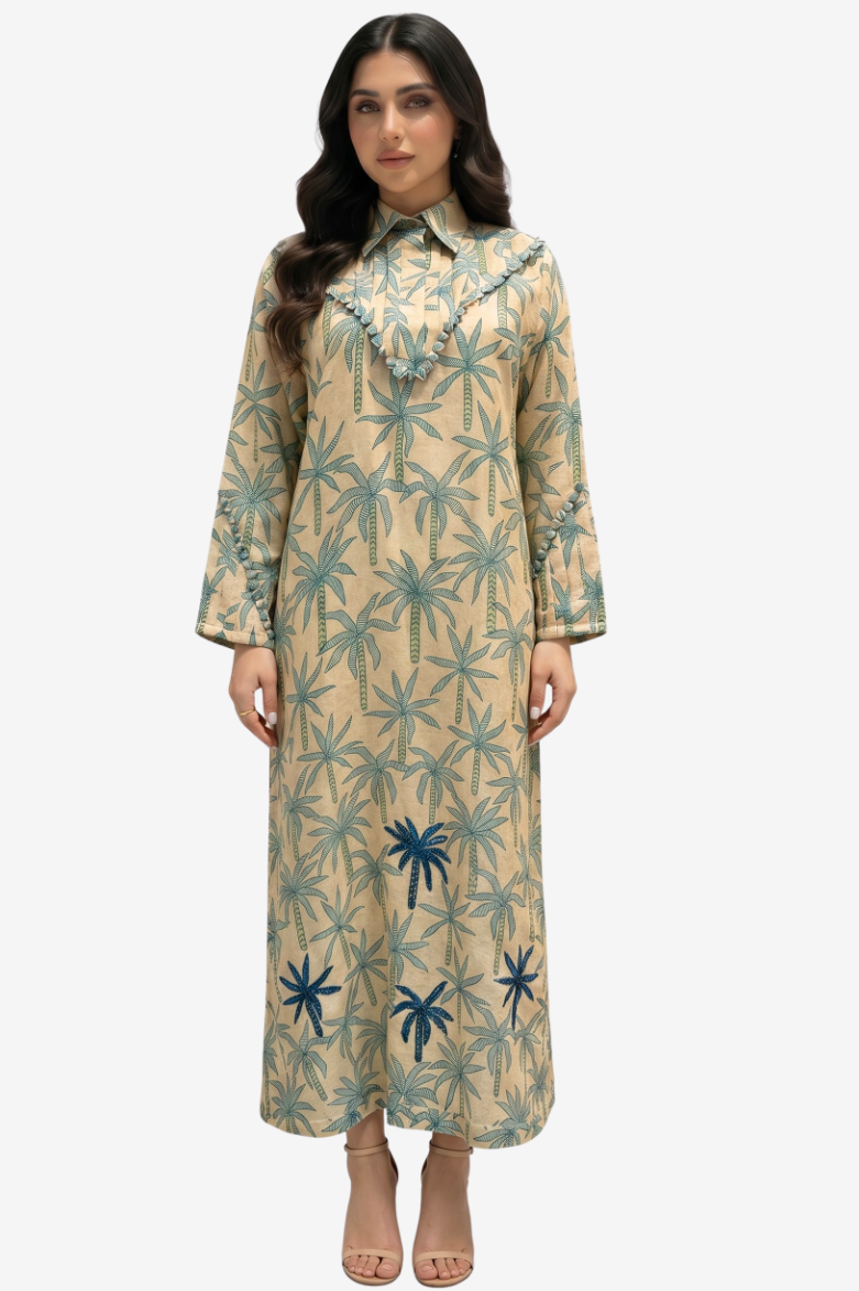 A woman modeling a long-sleeved beige maxi dress with a blue palm tree pattern, standing against a light gray background.