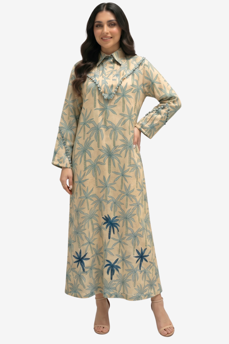 A woman modeling a long-sleeved beige maxi dress with a blue palm tree pattern, standing against a light gray background.
