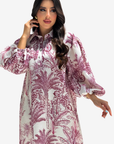 A woman modeling a long-sleeved white tunic dress with a dusty rose botanical palm tree print, set against a plain light gray background.