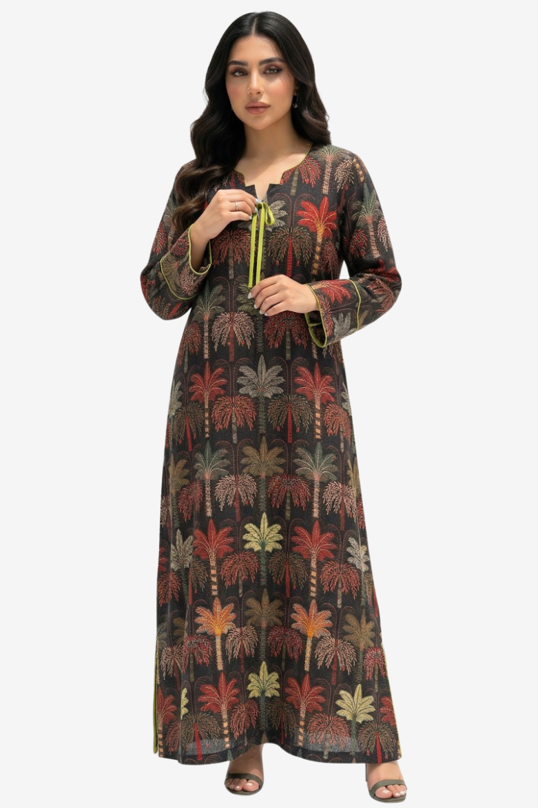 A woman modeling a long-sleeved, floor-length tunic dress with a dark brown base and an all-over palm tree print in red, green, and beige, featuring a lime green drawstring at the neckline.