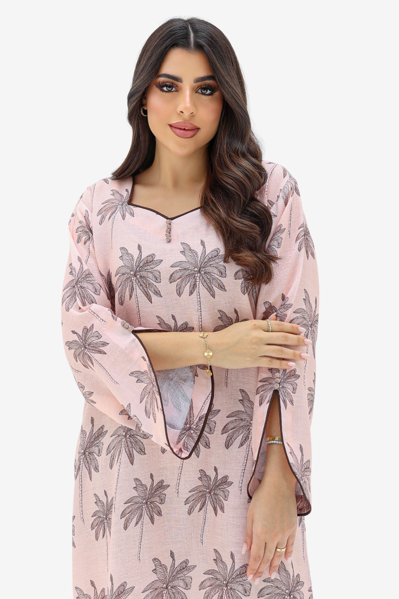 A woman modeling a light pink kurta with a gray palm tree print, featuring wide bell sleeves and a split neckline with a small gold zipper detail.