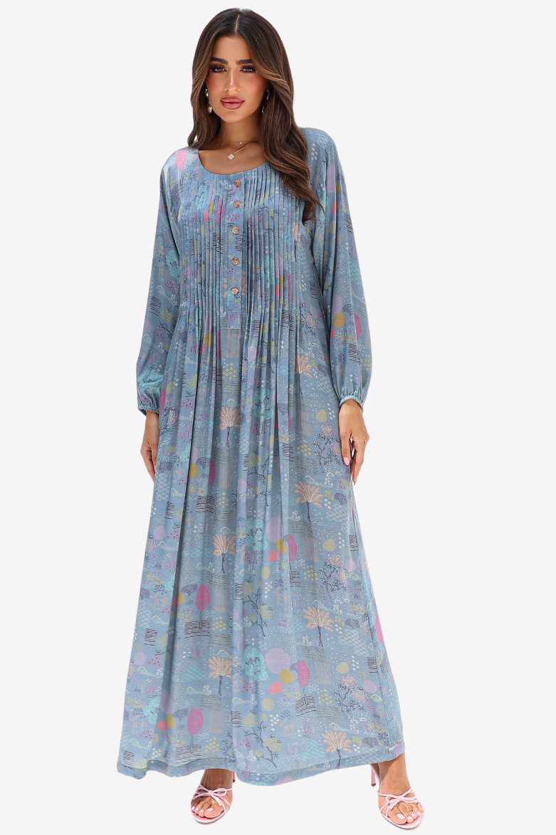 A woman modeling a long-sleeve, floor-length blue maxi dress with a pastel multicolor floral print, set against a plain light gray background.
