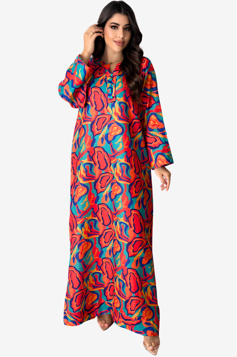 A woman modeling a long-sleeved maxi dress with a vibrant, multicolored abstract pattern in red, orange, blue, and yellow on a light gray background.
