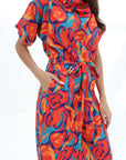 Close-up of the Prism Flow Sunset Abstract Linen Blend Jumpsuit highlighting the abstract print, draped neckline and self-tie waist belt.