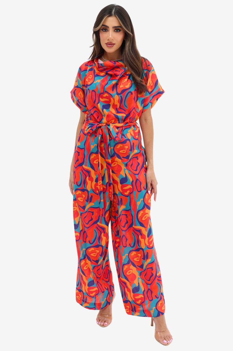 Prism Flow Sunset Abstract Linen Blend Jumpsuit by Gharza Couture featuring a vibrant multicolour abstract print, draped neckline, tie waist and wide-leg silhouette.