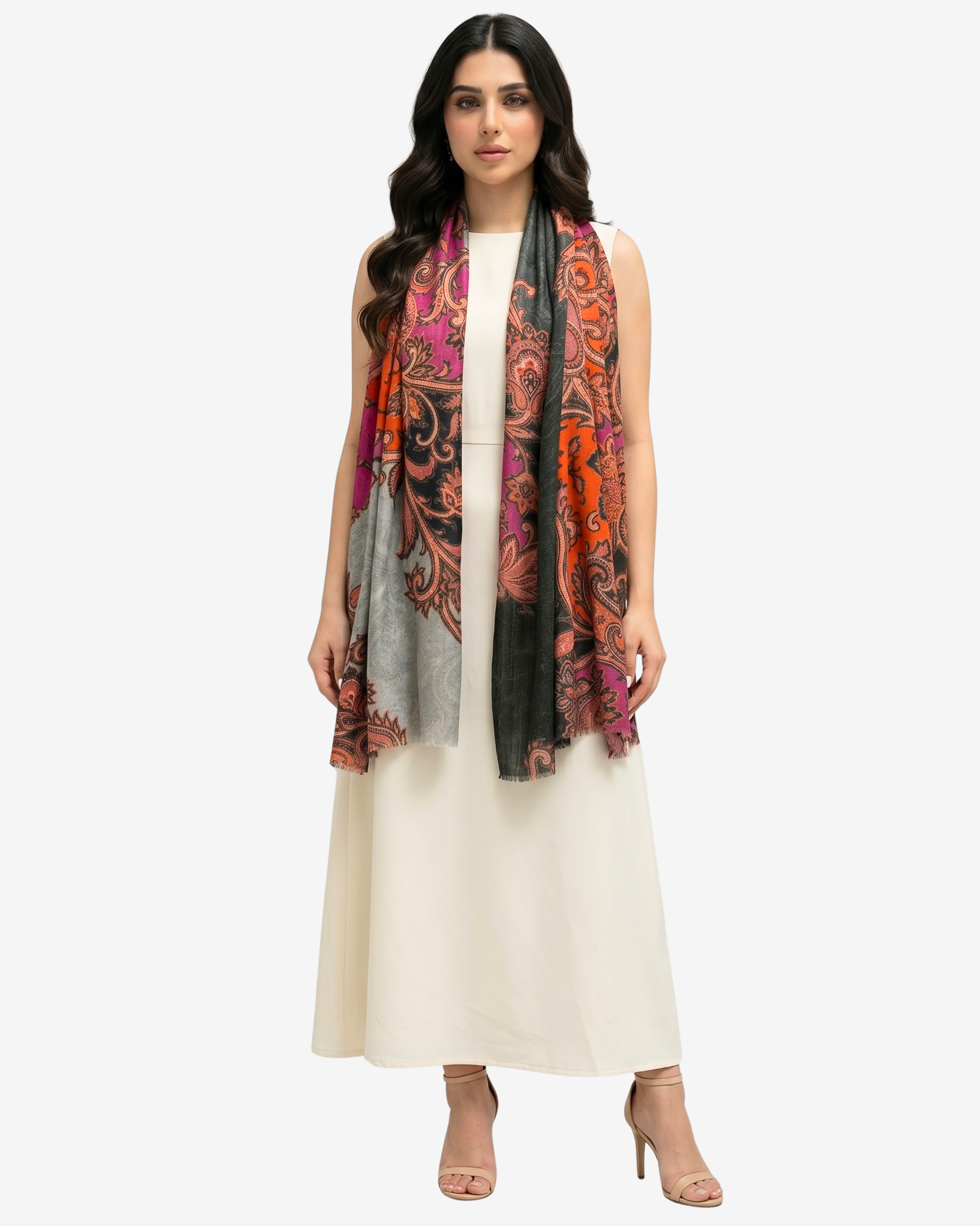 A woman modeling a long, lightweight scarf with a vibrant multicolor paisley pattern in orange, pink, black, and gray, worn over a cream-colored dress against a light gray studio background.