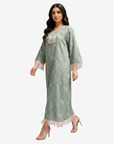 Side walking view of the Sage Mirage Fringe Detail Linen Blend Jalabiya featuring V-neck and fringe tassels.