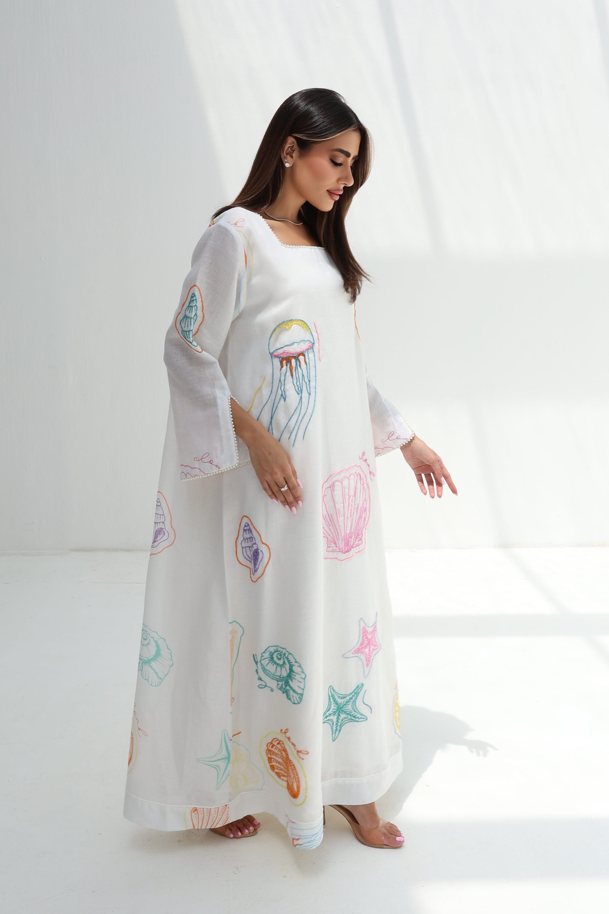 Side view of Seashell Embellished Linen Blend Jalabiya showing flowing full-length silhouette