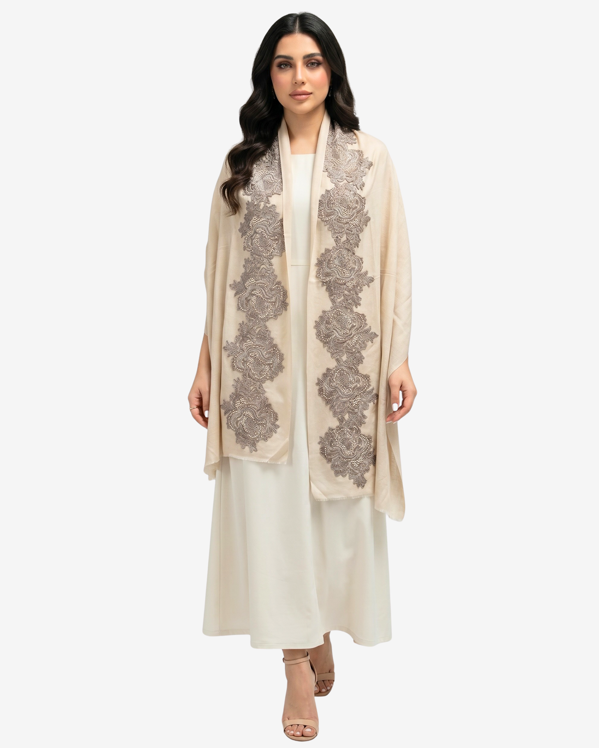 A woman modeling a long cream-colored shawl with intricate gray floral embroidery, worn over a matching cream kurta and trousers set, against a solid light gray background.