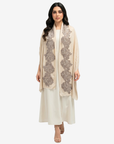 A woman modeling a long cream-colored shawl with intricate gray floral embroidery, worn over a matching cream kurta and trousers set, against a solid light gray background.