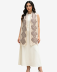 A woman modeling a sleeveless cream dress with a matching draped scarf featuring large gray floral lace patterns, set against a plain light gray background.