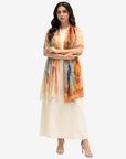 A woman modeling a cream-colored kurta and dupatta set with a vibrant, multicolored printed shawl draped over her shoulders, set against a plain light gray background.