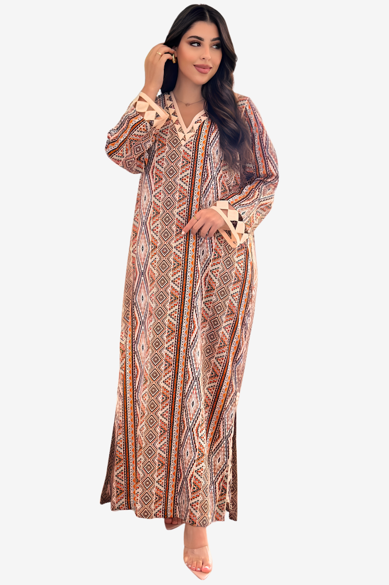 A woman modeling a long, loose maxi dress with a geometric tribal pattern in brown, beige, and orange tones, set against a plain light gray background.