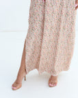 Person wearing a long, light-colored dress with floral pattern on a white background