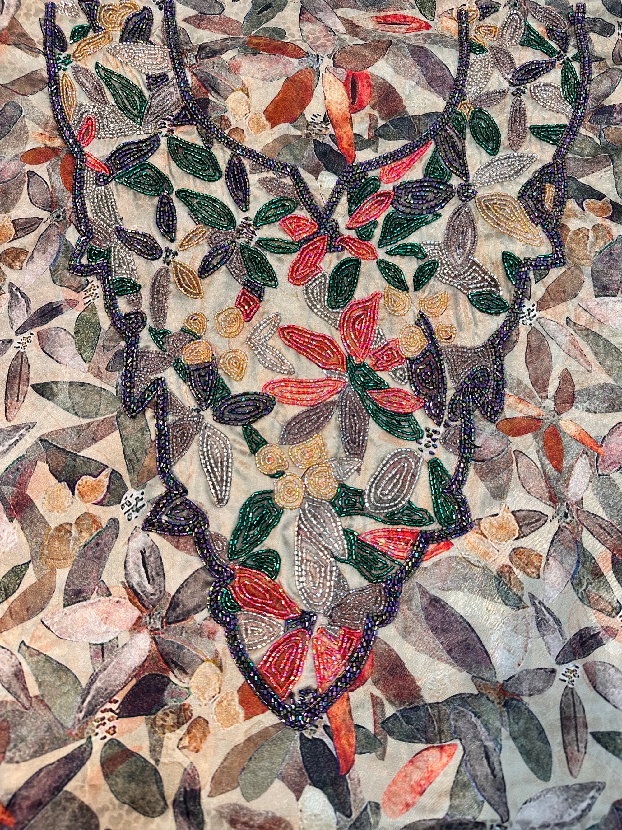 Close-up of Emerald Botanica silk fabric with green coral gold and silver hand beaded neckline