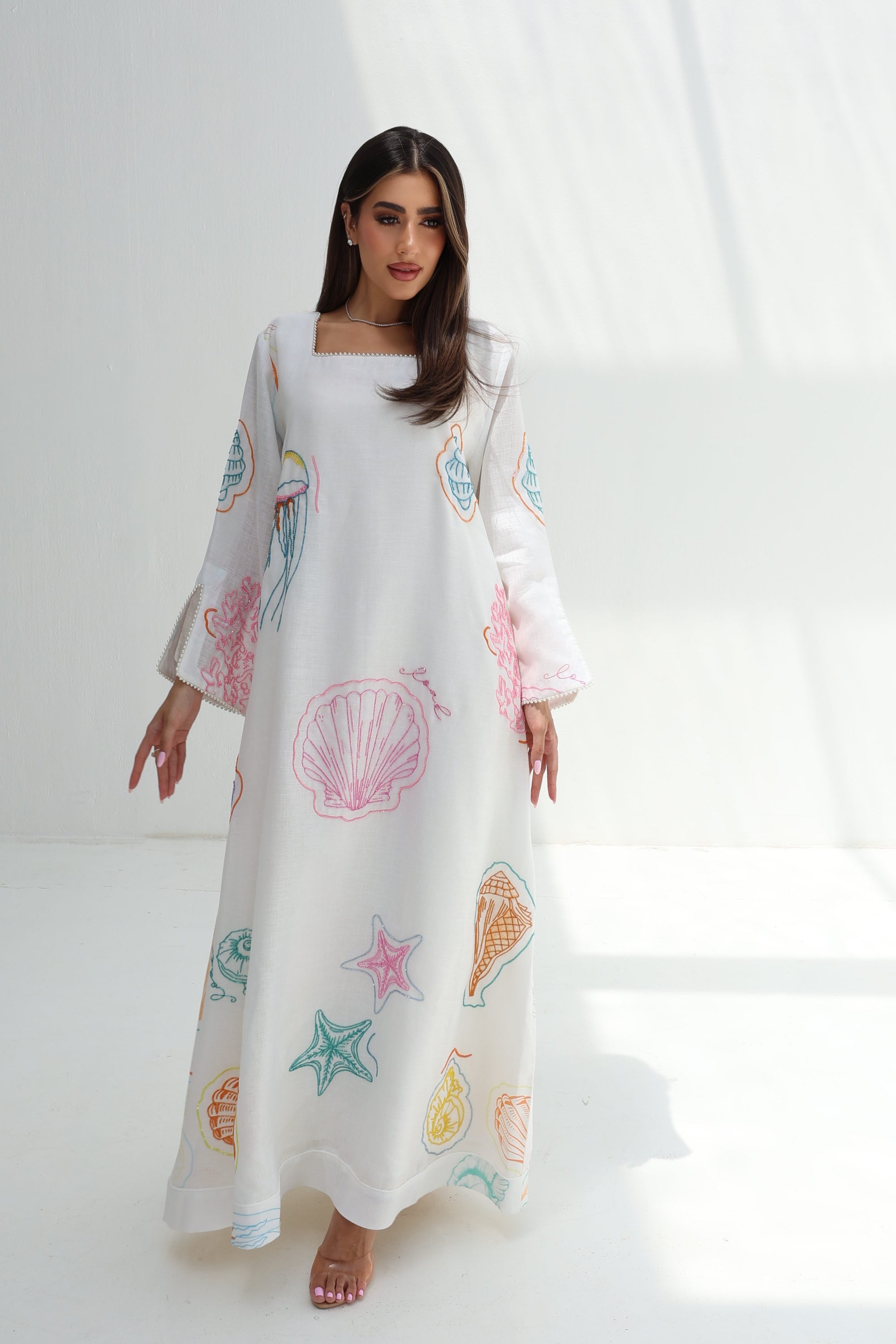 Full-length view of Seashell Embellished Linen Blend Jalabiya with white base and colorful seashell print