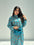 Woman wearing a blue traditional outfit with floral patterns on a gray background