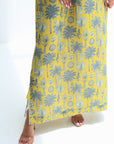 Person wearing a yellow skirt with a gray floral pattern on a white background