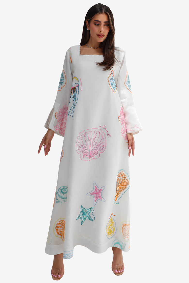 A woman modeling a long white maxi dress with a colorful seashell and starfish print, featuring wide three-quarter sleeves and a square neckline, set against a plain light gray background.