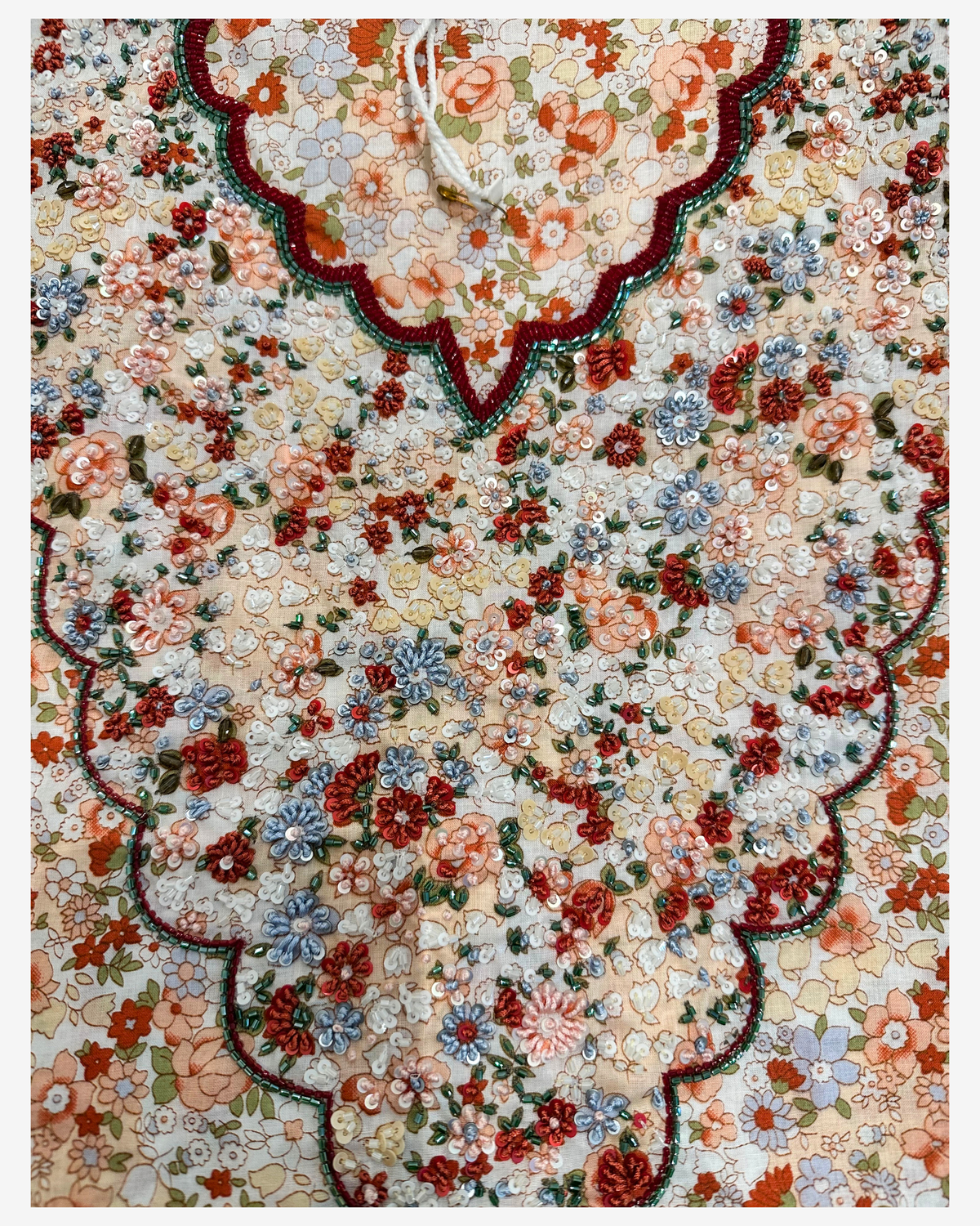 Close-up of the scalloped neckline with rust, blue, ivory and peach floral beadwork on the Vintage Bloom mukhawar.